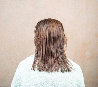 Kadın sırtı kameraya dönük, saçı kısa kesilmiş olarak oturuyor. Saç bakımı.