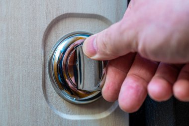 Yuvarlak kapı mandalında insan elinin yakın çekimi. Kapı mobilyası. Seçici odaklanma. Kilide odaklan..