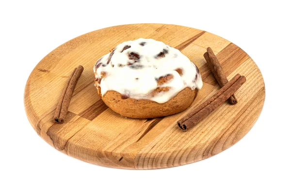 Beyaz arka planda kesme tahtasına şeker kaplı tatlı tarçınlı çörek. Tarçın çubukları. Ev yapımı çörekler..