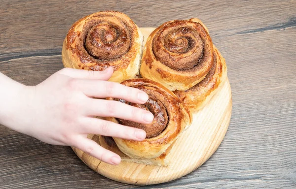 Selektiver Fokus. Eine Frauenhand greift nach den Brötchen. Fokus auf Brötchen. — Stockfoto