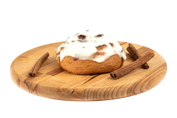 Cinnabon bun covered with icing sugar and cinnamon sticks on a cutting board. — Stock Photo, Image