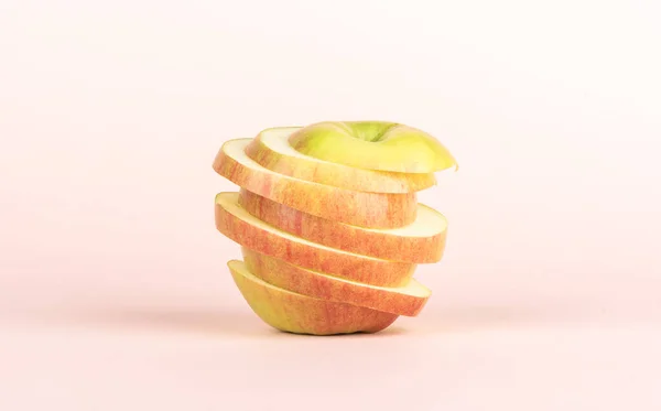 Нарізане яблуко ізольоване на блідо-рожевому фоні . — стокове фото