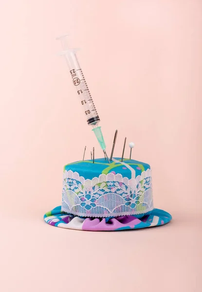 A medical syringe in a needle pad among sewing needles. Copy space.