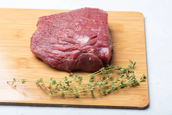 Carne cruda en una tabla de cortar de madera con tomillo. — Foto de Stock