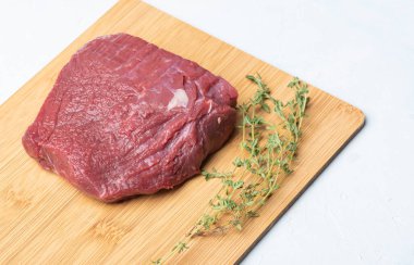 Tahta kesme tahtasında kekik ile çiğ et..