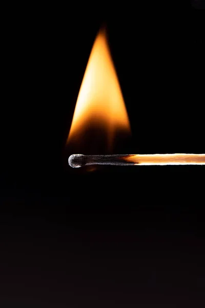 Треугольное пламя огня на спичке на черном фоне. — стоковое фото