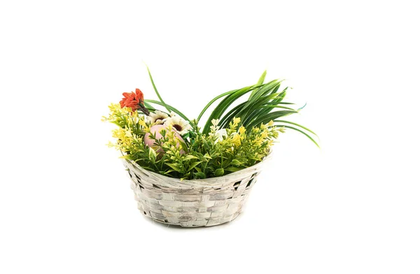 Artificial flowers and Easter eggs in a wicker basket over white background. — Stockfoto