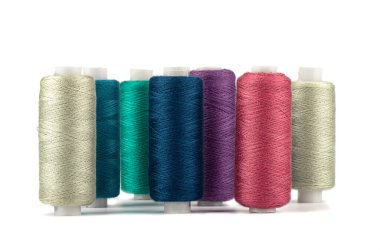 Beyaz arka planda farklı renklerde iplik makaraları. Boşluğu kopyala.