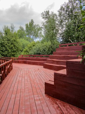 Kamu parkında oturma alanı olan yeni boyanmış bir çevre yolu. Yürüyüş için tahta döşeme.