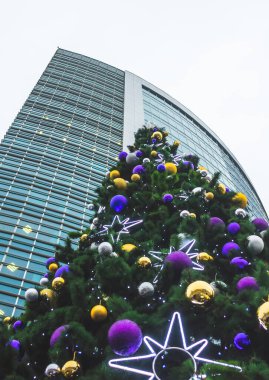 Sis kaplı bir gökdelenin arka planındaki Noel ağacı.