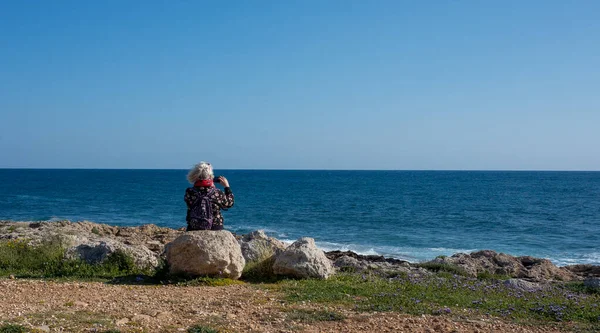 Пожилая Женщина Седыми Волосами Фотографирует Телефон Волны Пляже Солнечный Ветреный — стоковое фото