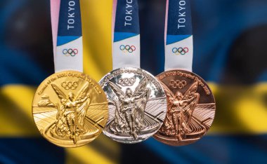 25 Nisan 2021 Tokyo, Japonya. 2020 Yaz Olimpiyatları 'nın altın, gümüş ve bronz madalyaları İsveç bayrağının arka planında Tokyo' da bulunmaktadır..