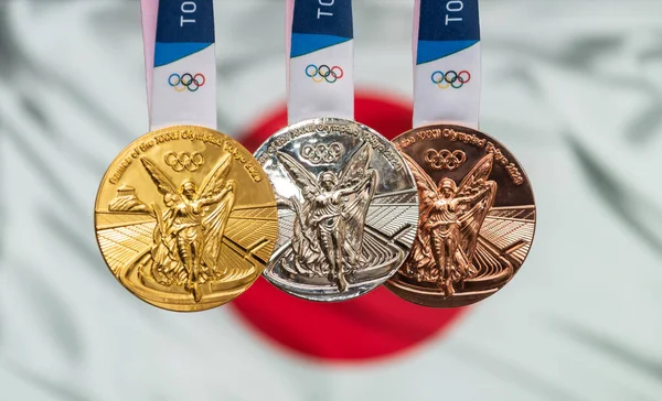 25 Nisan 2021 Tokyo, Japonya. Japonya bayrağının arka planında, 2020 Tokyo Olimpiyat Oyunları 'nın altın, gümüş ve bronz madalyaları yer alıyor..