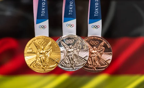 25 Nisan 2021 Tokyo, Japonya. Almanya bayrağının arka planında 2020 Tokyo Olimpiyat Oyunları 'nın altın, gümüş ve bronz madalyaları yer alıyor..