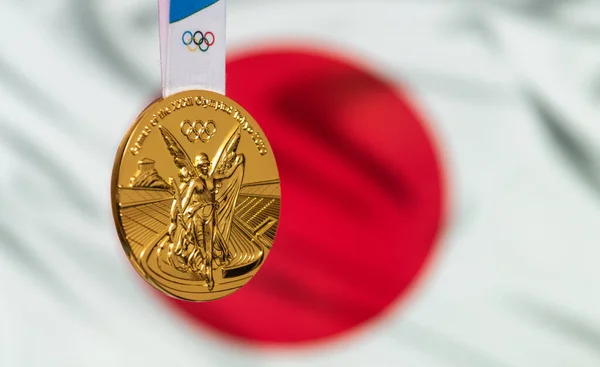 2021年4月25日東京都 日本の国旗を背景に東京で開催される第12回夏季オリンピックの金メダル — ストック写真