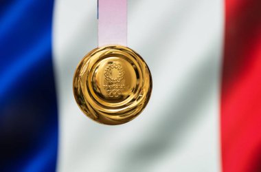 25 Nisan 2021 Tokyo, Japonya. Tokyo 'da düzenlenen XXXII Yaz Olimpiyat Oyunları' nın altın madalyası Fransa bayrağının arka planında.