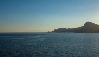 Kayalar, ılık bir yaz akşamında gün batımında hafif deniz dalgaları.