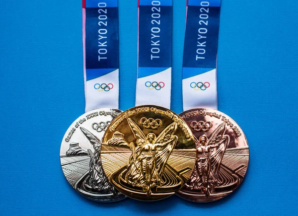 25 Nisan 2021 Tokyo, Japonya. Tokyo 'da düzenlenen XXII Yaz Olimpiyat Oyunlarının altın, gümüş ve bronz madalyaları mavi arka planda.