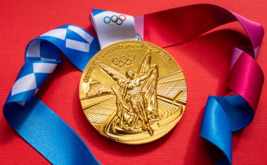 25 Nisan 2021 Tokyo, Japonya. Tokyo 'da düzenlenen XXXII Yaz Olimpiyat Oyunları' nın altın madalyası kırmızı arka planda.