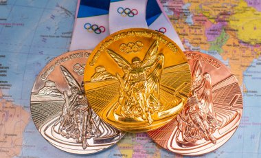 25 Nisan 2021 Tokyo, Japonya. Tokyo 'da düzenlenen XXII Yaz Olimpiyat Oyunları' nın altın, gümüş ve bronz madalyaları dünya haritasının arka planına karşıdır..