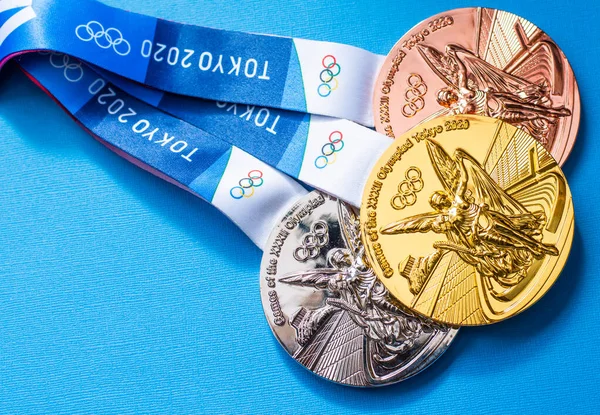 25 Nisan 2021 Tokyo, Japonya. Tokyo 'da düzenlenen XXII Yaz Olimpiyat Oyunlarının altın, gümüş ve bronz madalyaları mavi arka planda.