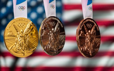 25 Nisan 2021 Tokyo, Japonya. 2020 Tokyo Olimpiyat Oyunları 'nın altın, gümüş ve bronz madalyaları ABD bayrağının arka planında.