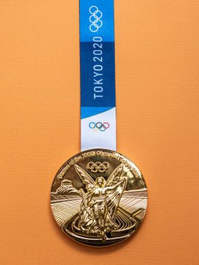 25 Nisan 2021 Tokyo, Japonya. Tokyo 'da düzenlenen XXXII Yaz Olimpiyat Oyunları' nın altın madalyası sarı arka planda.
