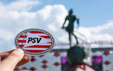 14 Haziran 2021 Eindhoven, Hollanda. PSV Eindhoven futbol kulübünün amblemi modern bir stadyumun arka planına karşıdır..