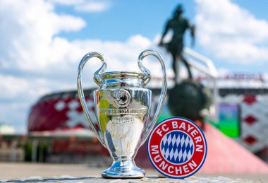 14 Haziran 2021 Münih, Almanya. FC Bayern Münih futbol kulübü ve UEFA Şampiyonlar Ligi Kupası 'nın amblemi modern bir stadyumun arka planına karşıdır..