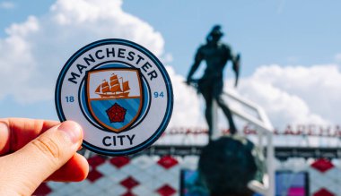 14 Haziran 2021 Manchester, İngiltere. Manchester City futbol kulübünün amblemi modern bir stadyumun arka planına karşı..