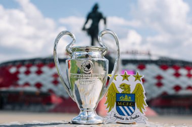 14 Haziran 2021 Manchester, İngiltere. Manchester City futbol kulübünün amblemi ve UEFA Şampiyonlar Ligi Kupası modern bir stadyumun arka planına karşı..