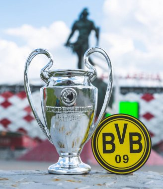 14 Haziran 2021 Dortmund, Almanya. Borussia Dortmund futbol kulübü ve UEFA Şampiyonlar Ligi Kupası 'nın amblemi modern bir stadyumun arka planına karşıdır..