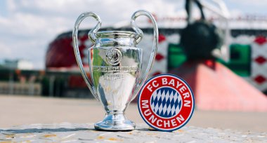 14 Haziran 2021 Münih, Almanya. FC Bayern Münih futbol kulübü ve UEFA Şampiyonlar Ligi Kupası 'nın amblemi modern bir stadyumun arka planına karşıdır..