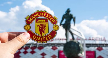 14 Haziran 2021 Manchester, İngiltere. Manchester United F.C. Modern bir stadyumun arka planına karşı futbol kulübü amblemi..