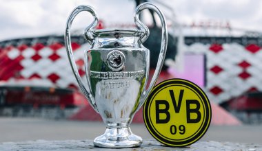 14 Haziran 2021 Dortmund, Almanya. Borussia Dortmund futbol kulübü ve UEFA Şampiyonlar Ligi Kupası 'nın amblemi modern bir stadyumun arka planına karşıdır..