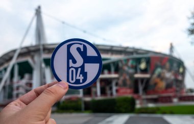 30 Ağustos 2021, Gelsenkirchen, Almanya. Futbol kulübü FC Schalke 04 'ün amblemi modern stadyumun arka planına karşıdır..