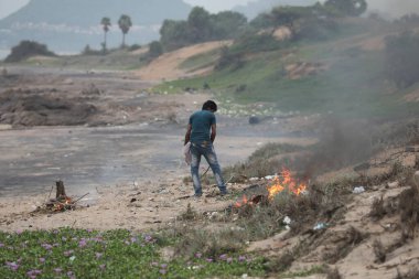 İşçiler sahile çöp atıyor.