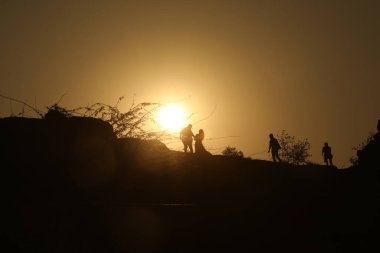 Tepedeki insanların siluetleri.