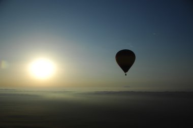 Sıcak hava balonu çöl kumunun üzerinde yüzüyor.