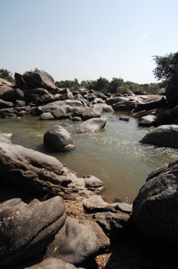 Su yosunlu kayaların arasından akıyor.