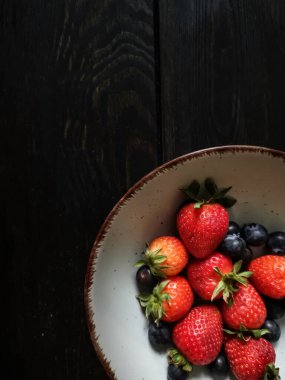 Parlak tabakta taze çilek ve yabanmersini.
