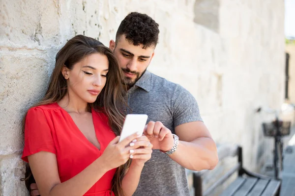 Young couple are looking at a mobile device.