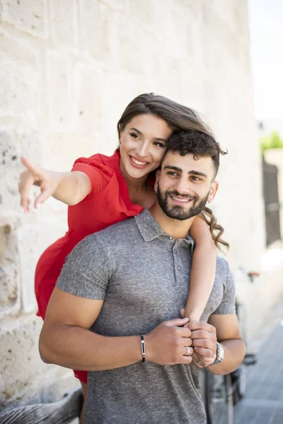 Young Couple Wearing Vacation Clothes Hugging Showing Direction While Smiling Royalty Free Stock Photos