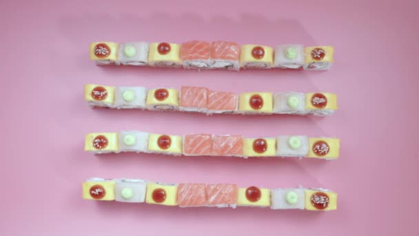 Composizione di diversi tipi di rotoli di sushi disposti su sfondo rosa — Video Stock