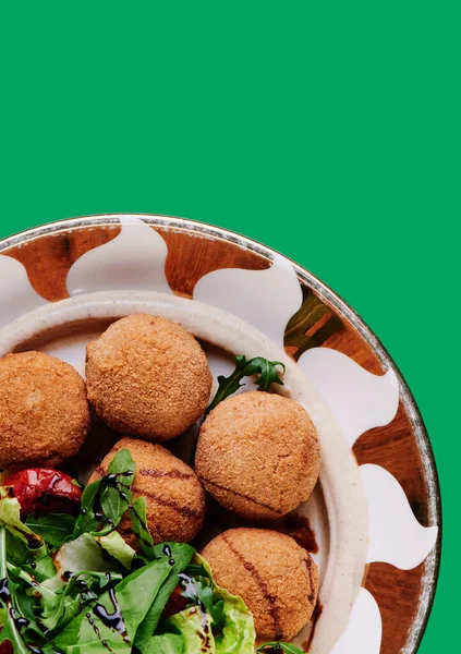 Schöne Falafel-Bällchen und frischer Salat auf einem Teller vor grünem Hintergrund. Raum für Text. Nahaufnahme. Foto für Menü und Website — Stockfoto