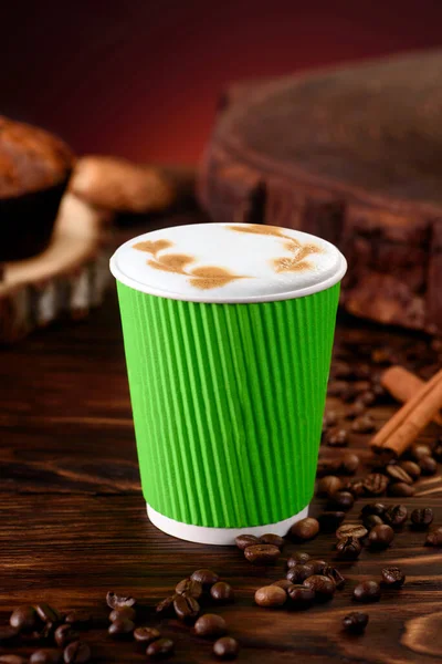 Café con leche en taza de papel verde sobre fondo de madera. Burlarse. Cappuccino llevar. Espacio para texto. — Foto de Stock