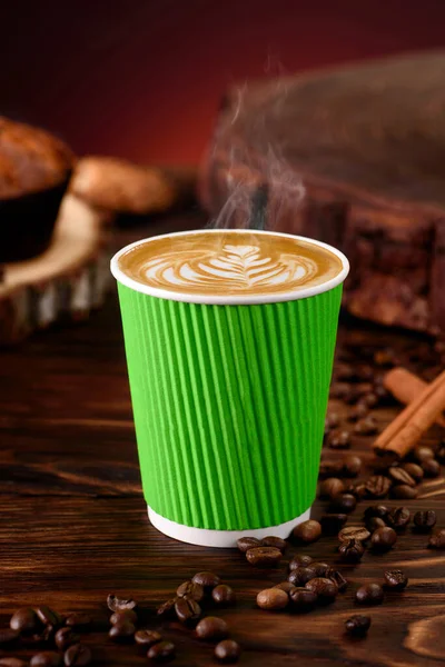 Café en taza de papel verde sobre fondo de madera. Burlarse. Cappuccino llevar. Espacio para texto. — Foto de Stock