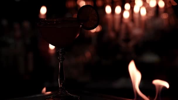 Cocktail in un elegante calice su fondo di fuoco. Primo piano. Bella atmosfera scura — Video Stock