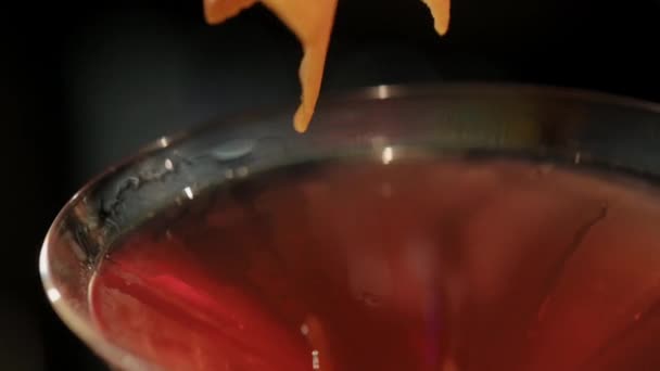 Le barman décore un cocktail rouge avec de la peau d'orange. cocktail dans un verre élégant. — Video