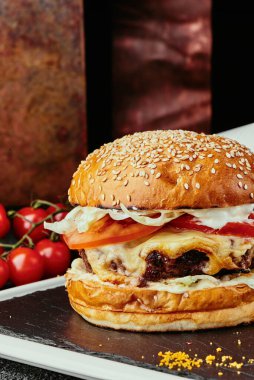 Büyük burger, sulu pirzola, peynir, domates, marul, patates kızartması ve barbekü sosuyla servis edilen bakır tabaklar. Kapat.